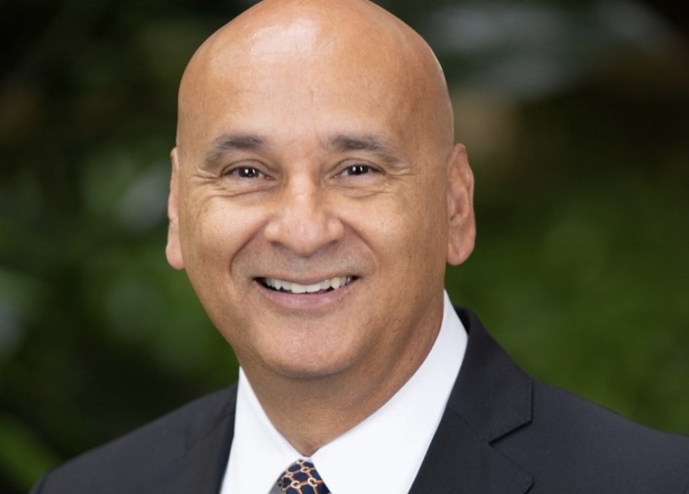 A man wearing a suit, smiling in a headshot.